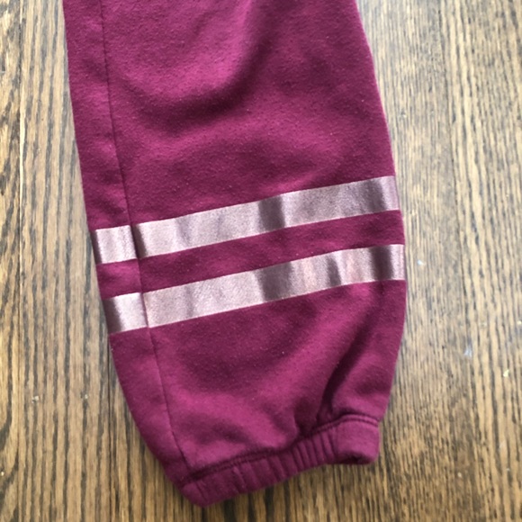 These are red sweatpants with two gold stripes. - Picture 3 of 4